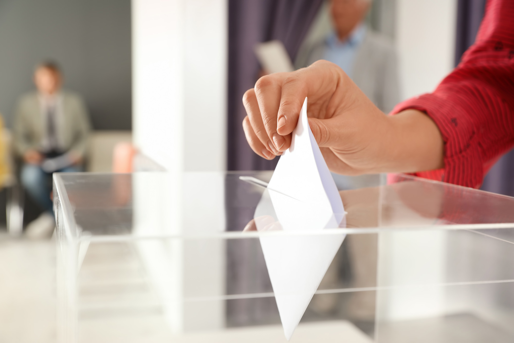 Woman drops ballot in ballot box.